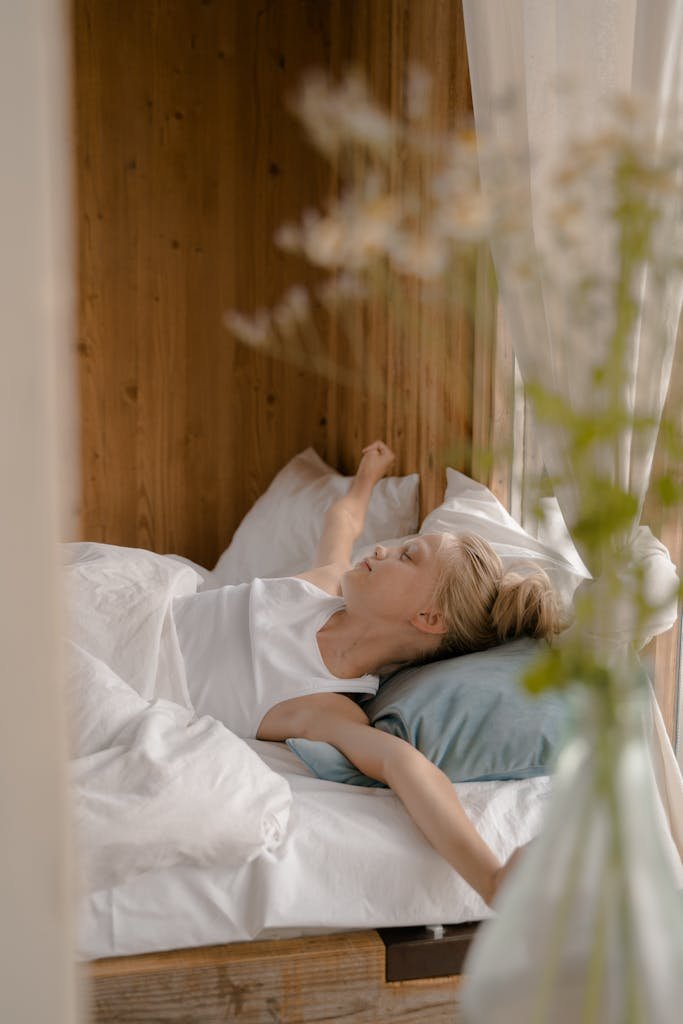 A young girl peacefully sleeping in a wooden interior bedroom with soft lighting.