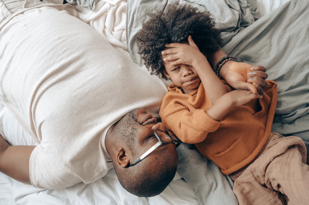 Man and child lying on bed, sharing a tender moment of playful bonding indoors.