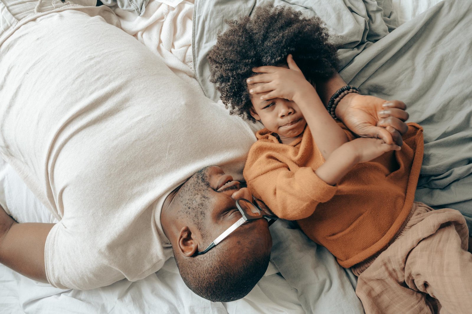 Man and child lying on bed, sharing a tender moment of playful bonding indoors.